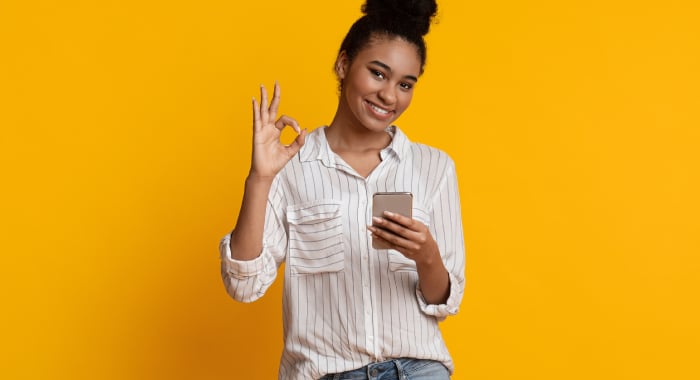 woman with a phone giving the okay sign
