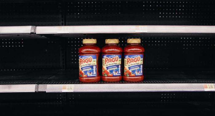 Grocery store aisle with only three jars of pasta sauce left on the shelf
