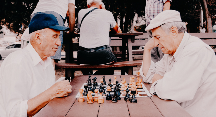 two elderly people playing chess outside