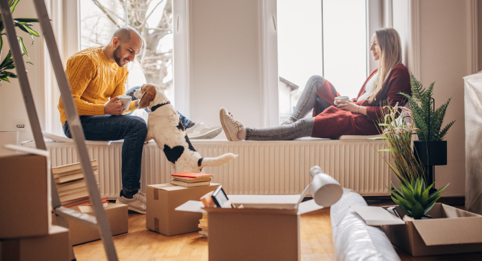 two people in their home with their dog and moving boxes