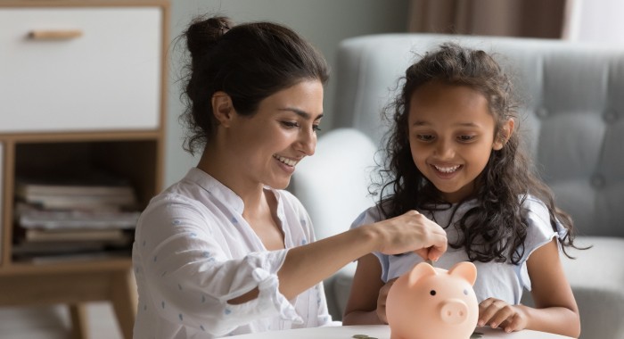 parent showing young child how to use a piggy bank