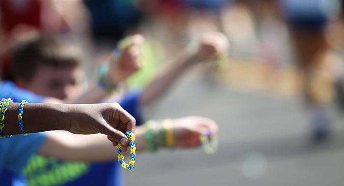 People along the sidelines of a race handing out bracelets in Boston Marathon colors to runners